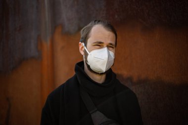 Şehrin sokaklarında maske takan yakışıklı bir adam. Grip virüsü veya koronavirüs enfeksiyonuna karşı korunmak için solunum cihazına bağlı bir gencin yakın çekimi.