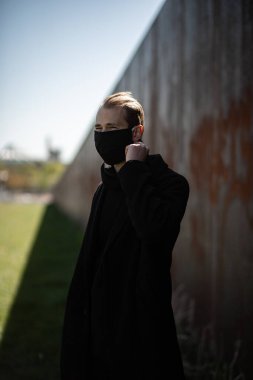 Şehrin sokaklarında maske takan yakışıklı bir adam. Grip virüsü veya koronavirüs enfeksiyonuna karşı korunmak için solunum cihazına bağlı bir gencin yakın çekimi.