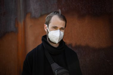 Şehrin sokaklarında maske takan yakışıklı bir adam. Grip virüsü veya koronavirüs enfeksiyonuna karşı korunmak için solunum cihazına bağlı bir gencin yakın çekimi.