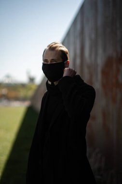 Şehrin sokaklarında maske takan yakışıklı bir adam. Grip virüsü veya koronavirüs enfeksiyonuna karşı korunmak için solunum cihazına bağlı bir gencin yakın çekimi.