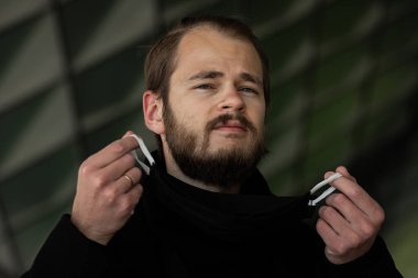 Şehrin sokaklarında maske takan yakışıklı bir adam. Grip virüsü veya koronavirüs enfeksiyonuna karşı korunmak için solunum cihazına bağlı bir gencin yakın çekimi.