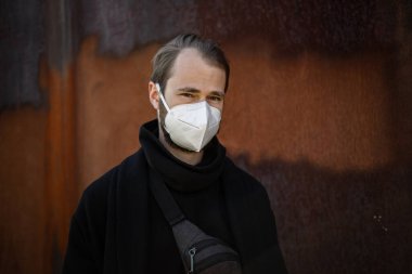 Şehrin sokaklarında maske takan yakışıklı bir adam. Grip virüsü veya koronavirüs enfeksiyonuna karşı korunmak için solunum cihazına bağlı bir gencin yakın çekimi.