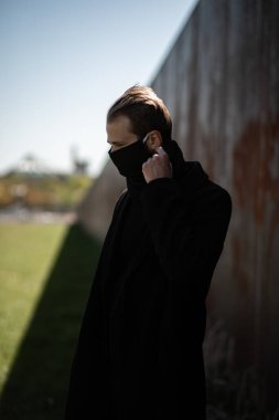 Şehrin sokaklarında maske takan yakışıklı bir adam. Grip virüsü veya koronavirüs enfeksiyonuna karşı korunmak için solunum cihazına bağlı bir gencin yakın çekimi.