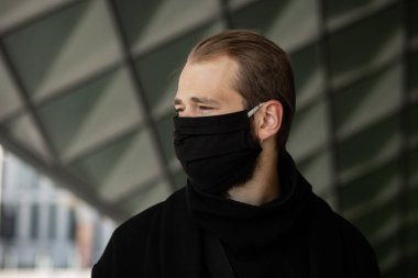 Şehrin sokaklarında maske takan yakışıklı bir adam. Grip virüsü veya koronavirüs enfeksiyonuna karşı korunmak için solunum cihazına bağlı bir gencin yakın çekimi.