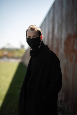 Şehrin sokaklarında maske takan yakışıklı bir adam. Grip virüsü veya koronavirüs enfeksiyonuna karşı korunmak için solunum cihazına bağlı bir gencin yakın çekimi.