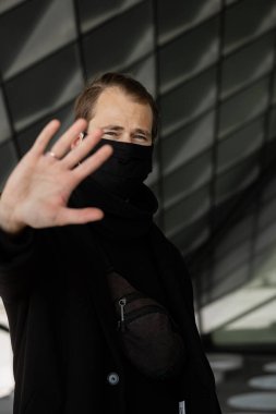 Şehrin sokaklarında maske takan yakışıklı bir adam. Grip virüsü veya koronavirüs enfeksiyonuna karşı korunmak için solunum cihazına bağlı bir gencin yakın çekimi.