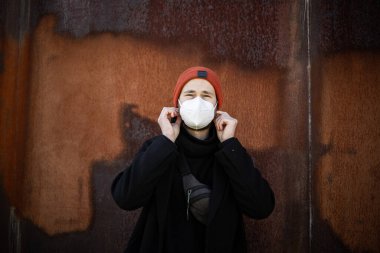 Şehrin sokaklarında maske takan yakışıklı bir adam. Grip virüsü veya koronavirüs enfeksiyonuna karşı korunmak için solunum cihazına bağlı bir gencin yakın çekimi.