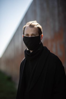 Şehrin sokaklarında maske takan yakışıklı bir adam. Grip virüsü veya koronavirüs enfeksiyonuna karşı korunmak için solunum cihazına bağlı bir gencin yakın çekimi.