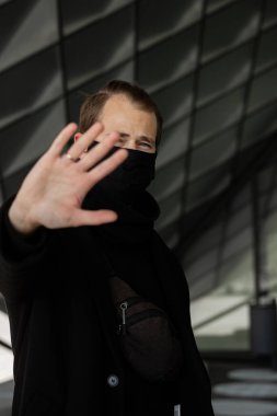 Şehrin sokaklarında maske takan yakışıklı bir adam. Grip virüsü veya koronavirüs enfeksiyonuna karşı korunmak için solunum cihazına bağlı bir gencin yakın çekimi.