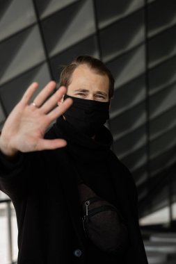Şehrin sokaklarında maske takan yakışıklı bir adam. Grip virüsü veya koronavirüs enfeksiyonuna karşı korunmak için solunum cihazına bağlı bir gencin yakın çekimi.