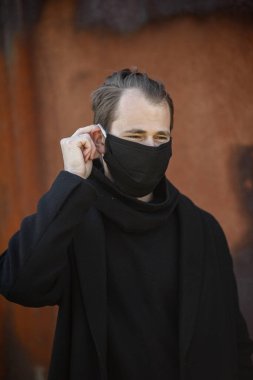 Şehrin sokaklarında maske takan yakışıklı bir adam. Grip virüsü veya koronavirüs enfeksiyonuna karşı korunmak için solunum cihazına bağlı bir gencin yakın çekimi.