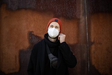 Şehrin sokaklarında maske takan yakışıklı bir adam. Grip virüsü veya koronavirüs enfeksiyonuna karşı korunmak için solunum cihazına bağlı bir gencin yakın çekimi.