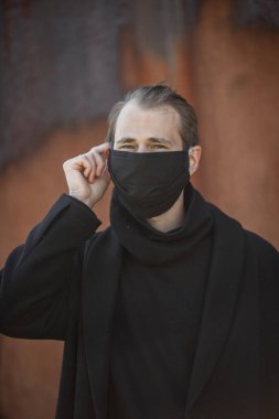 Şehrin sokaklarında maske takan yakışıklı bir adam. Grip virüsü veya koronavirüs enfeksiyonuna karşı korunmak için solunum cihazına bağlı bir gencin yakın çekimi.