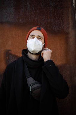 Şehrin sokaklarında maske takan yakışıklı bir adam. Grip virüsü veya koronavirüs enfeksiyonuna karşı korunmak için solunum cihazına bağlı bir gencin yakın çekimi.