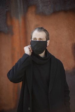 Şehrin sokaklarında maske takan yakışıklı bir adam. Grip virüsü veya koronavirüs enfeksiyonuna karşı korunmak için solunum cihazına bağlı bir gencin yakın çekimi.