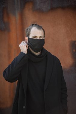 Şehrin sokaklarında maske takan yakışıklı bir adam. Grip virüsü veya koronavirüs enfeksiyonuna karşı korunmak için solunum cihazına bağlı bir gencin yakın çekimi.