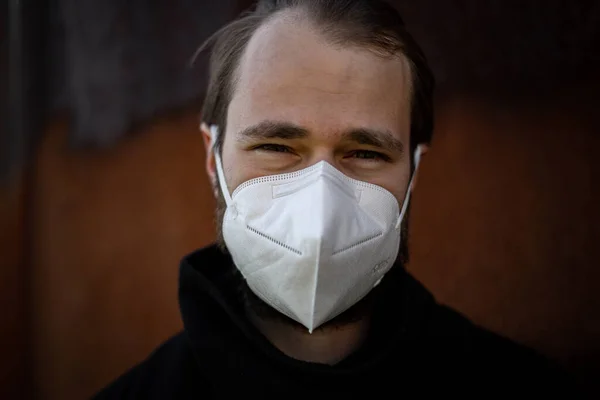 Handsome man wearing a mask on the streets of the city. Closeup of a young man in a respirator to protect against infection with influenza virus or coronavirus