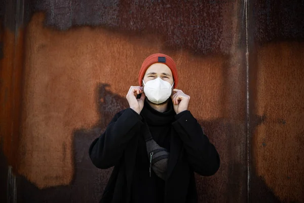 Şehrin sokaklarında maske takan yakışıklı bir adam. Grip virüsü veya koronavirüs enfeksiyonuna karşı korunmak için solunum cihazına bağlı bir gencin yakın çekimi.
