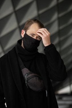 Şehrin sokaklarında maske takan yakışıklı bir adam. Grip virüsü veya koronavirüs enfeksiyonuna karşı korunmak için solunum cihazına bağlı bir gencin yakın çekimi.