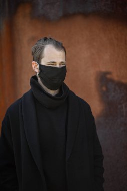 Şehrin sokaklarında maske takan yakışıklı bir adam. Grip virüsü veya koronavirüs enfeksiyonuna karşı korunmak için solunum cihazına bağlı bir gencin yakın çekimi.