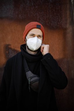 Şehrin sokaklarında maske takan yakışıklı bir adam. Grip virüsü veya koronavirüs enfeksiyonuna karşı korunmak için solunum cihazına bağlı bir gencin yakın çekimi.