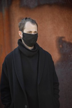 Şehrin sokaklarında maske takan yakışıklı bir adam. Grip virüsü veya koronavirüs enfeksiyonuna karşı korunmak için solunum cihazına bağlı bir gencin yakın çekimi.