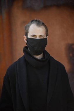 Şehrin sokaklarında maske takan yakışıklı bir adam. Grip virüsü veya koronavirüs enfeksiyonuna karşı korunmak için solunum cihazına bağlı bir gencin yakın çekimi.