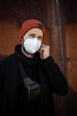 Şehrin sokaklarında maske takan yakışıklı bir adam. Grip virüsü veya koronavirüs enfeksiyonuna karşı korunmak için solunum cihazına bağlı bir gencin yakın çekimi.