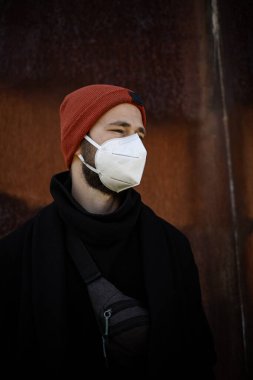 Şehrin sokaklarında maske takan yakışıklı bir adam. Grip virüsü veya koronavirüs enfeksiyonuna karşı korunmak için solunum cihazına bağlı bir gencin yakın çekimi.