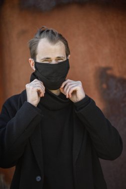 Şehrin sokaklarında maske takan yakışıklı bir adam. Grip virüsü veya koronavirüs enfeksiyonuna karşı korunmak için solunum cihazına bağlı bir gencin yakın çekimi.