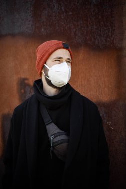 Şehrin sokaklarında maske takan yakışıklı bir adam. Grip virüsü veya koronavirüs enfeksiyonuna karşı korunmak için solunum cihazına bağlı bir gencin yakın çekimi.