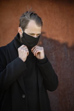 Şehrin sokaklarında maske takan yakışıklı bir adam. Grip virüsü veya koronavirüs enfeksiyonuna karşı korunmak için solunum cihazına bağlı bir gencin yakın çekimi.