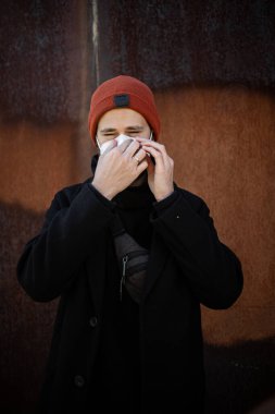 Şehrin sokaklarında maske takan yakışıklı bir adam. Grip virüsü veya koronavirüs enfeksiyonuna karşı korunmak için solunum cihazına bağlı bir gencin yakın çekimi.