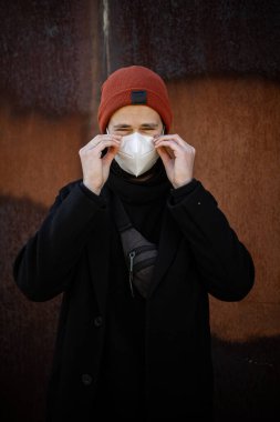 Şehrin sokaklarında maske takan yakışıklı bir adam. Grip virüsü veya koronavirüs enfeksiyonuna karşı korunmak için solunum cihazına bağlı bir gencin yakın çekimi.