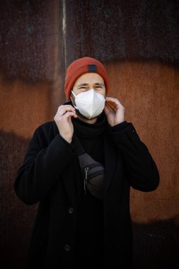 Şehrin sokaklarında maske takan yakışıklı bir adam. Grip virüsü veya koronavirüs enfeksiyonuna karşı korunmak için solunum cihazına bağlı bir gencin yakın çekimi.