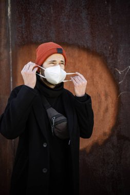 Şehrin sokaklarında maske takan yakışıklı bir adam. Grip virüsü veya koronavirüs enfeksiyonuna karşı korunmak için solunum cihazına bağlı bir gencin yakın çekimi.