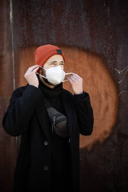 Şehrin sokaklarında maske takan yakışıklı bir adam. Grip virüsü veya koronavirüs enfeksiyonuna karşı korunmak için solunum cihazına bağlı bir gencin yakın çekimi.