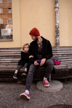 Güzel küçük bir kız ve babası boş bir sokakta bankta oturuyor, arkadaşlarını özlüyor. 