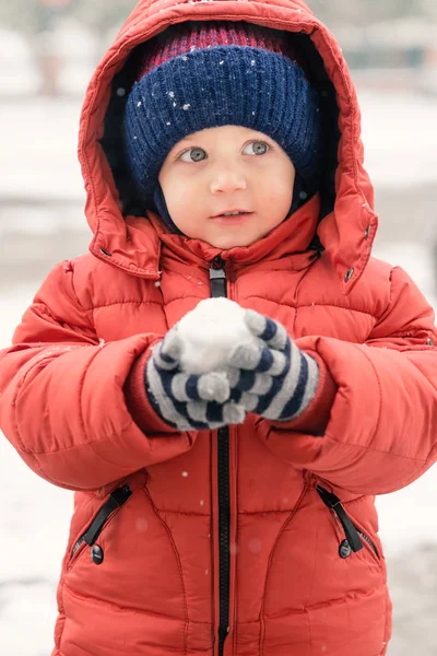 Sweet child in the snow with a snowball in his hands\