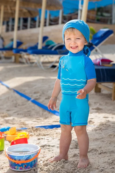 Bonito bebé sonriente juega en la playa — Foto de Stock