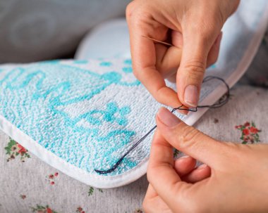 Needlewoman elbiselerini dikiyor.
