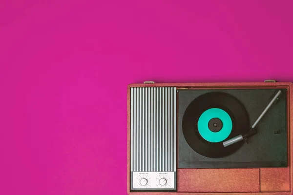 Retro vinyl player and turnable on a fuchsia background. Entertainment 70s. Listen to music. Top view.