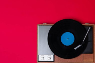 Klasik vinil çalar ve kırmızı arka planda döndürülebilir. Eğlence 70 'ler. Müzik dinle. Üst görünüm.