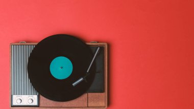 Klasik vinil çalar ve kırmızı arka planda döndürülebilir. Eğlence 70 'ler. Müzik dinle. Üst görünüm.