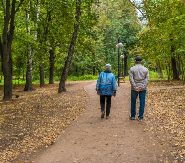 Yaşlı insanlar sonbaharda parkta birlikte yürürler..