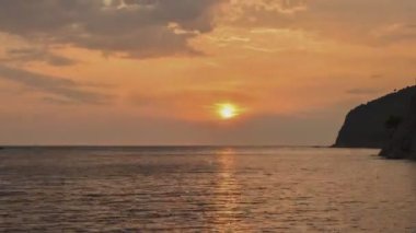 Karadağ. Turuncu gün batımı gökyüzü ve deniz yansıması. Yavaş bulutlar. Zaman aşımı 4k, 3840x2160. 