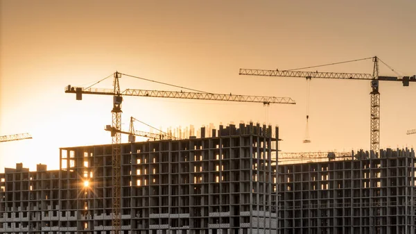 Baustelle Mit Kränen Bei Orangefarbenem Sonnenuntergang Arbeiten Mit Einbaumetall lizenzfreie Stockbilder