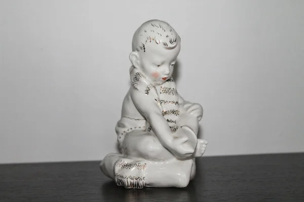Porcelain Figurine Boy Puts Sandalii — Zdjęcie stockowe