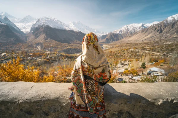 Geleneksel elbise giymiş bir kadın duvarda oturuyor ve sonbahar sezonunda Hunza Vadisi 'ne bakıyor, Pakistan' da Gilgit Baltistan, Asya