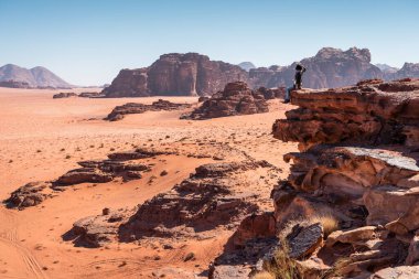 Kayaların üzerinde oturan ve Ürdün, Arap ve Asya 'daki Wadi Rum çölünün manzarasını arayan bir kadın gezgin.